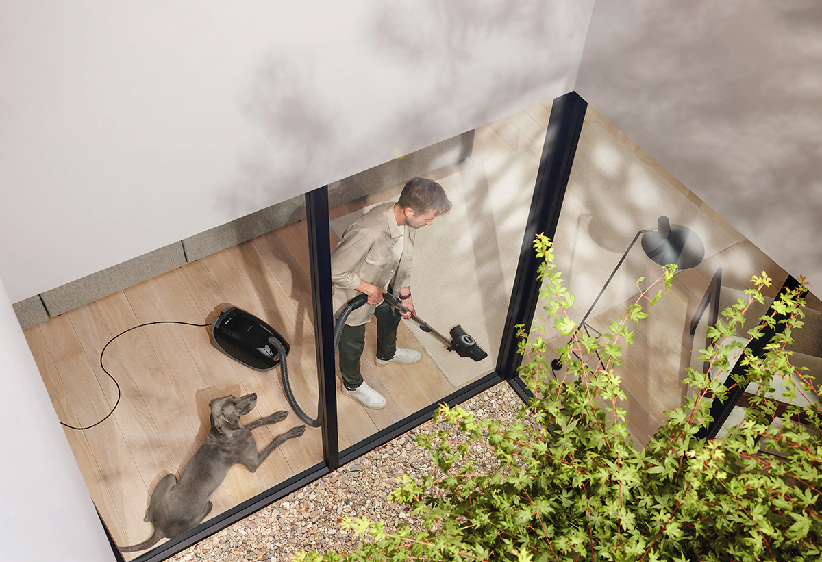 Ένας άντρας καθαρίζει το πάτωμα του σπιτιού του με τη σκούπα.